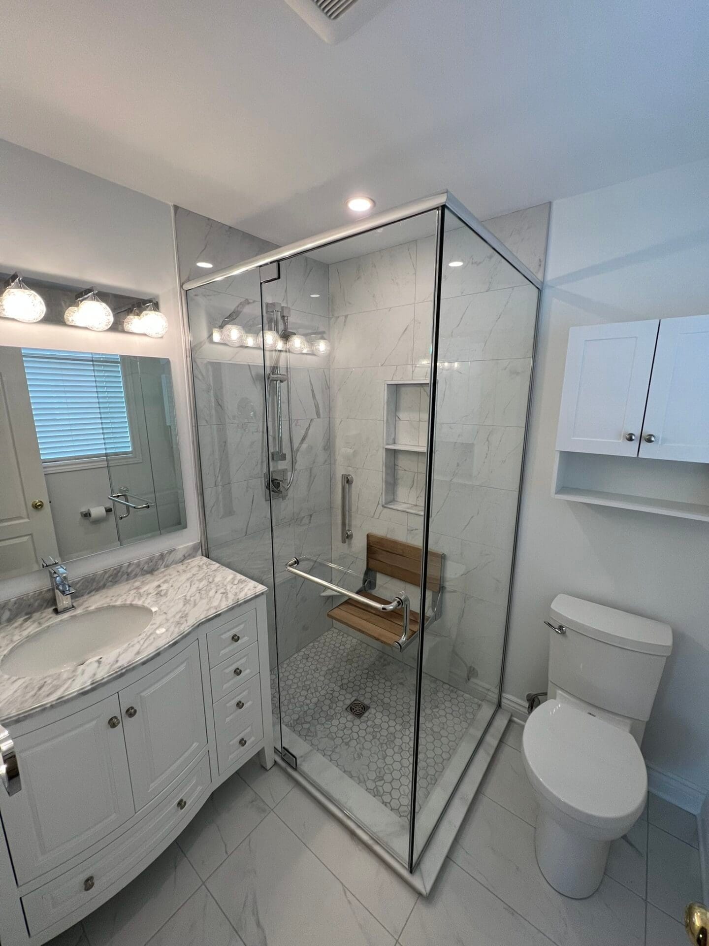 Accessible Bathroom Renovations for Seniors in Ottawa | Renos4Life Bright bathroom shower with glass enclosure, marble tiles, and built-in shelves.
